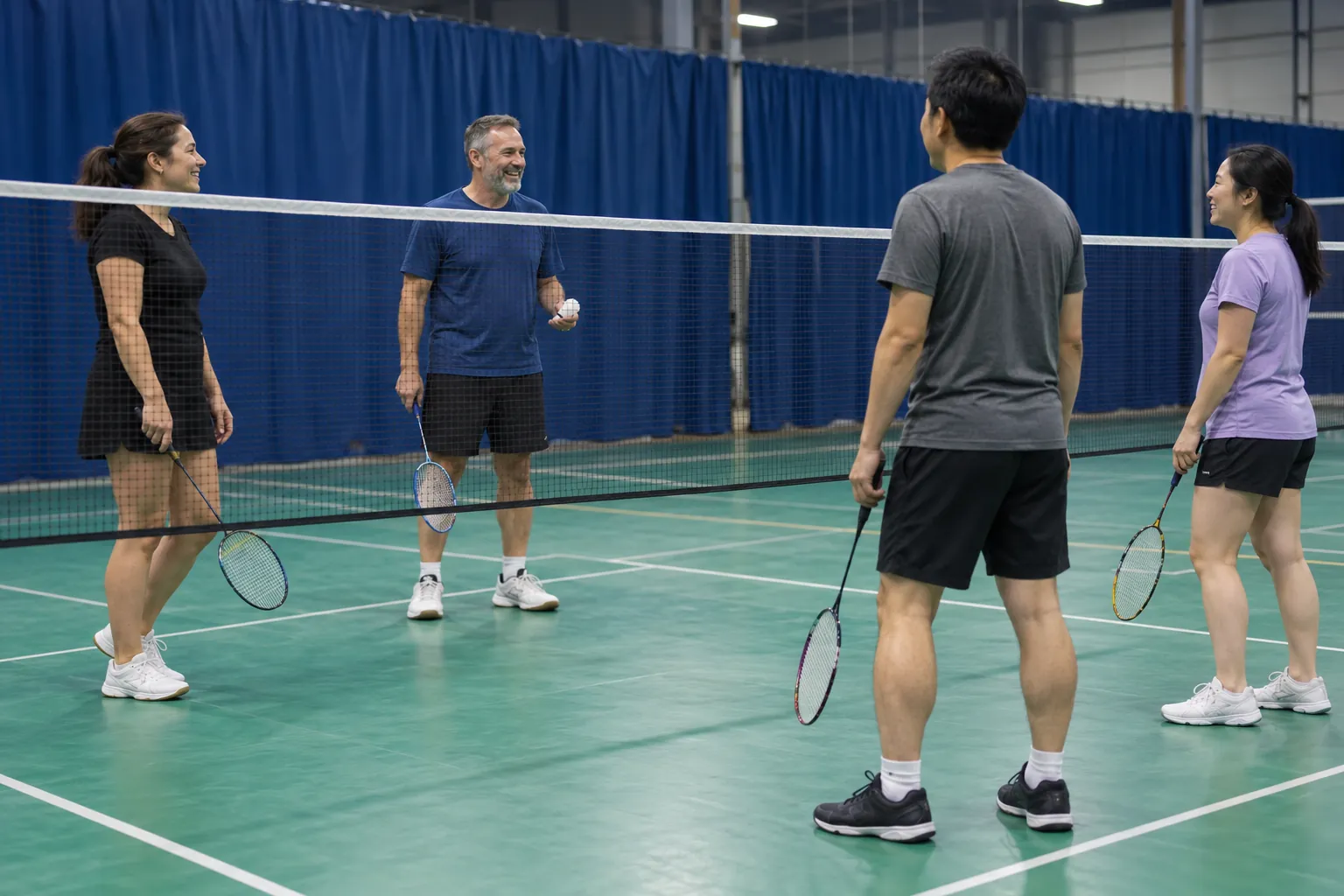 Four badminton players talking between rallies.