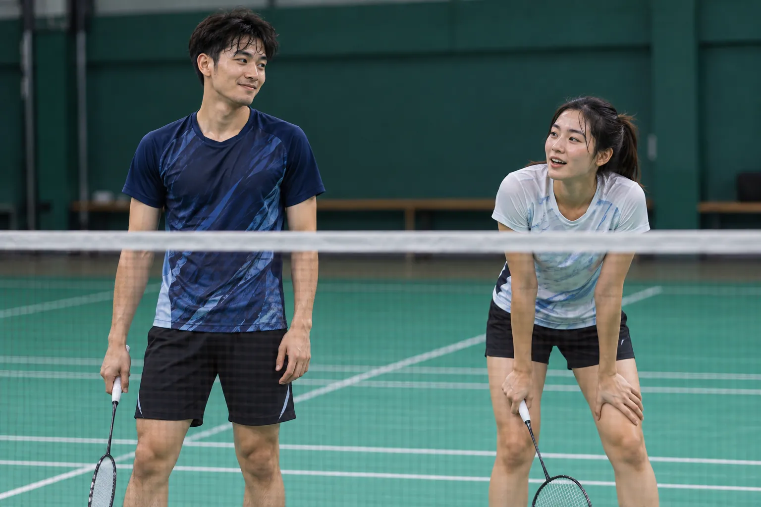 Illustration: Young badminton partners sharing a light moment after a rally.
