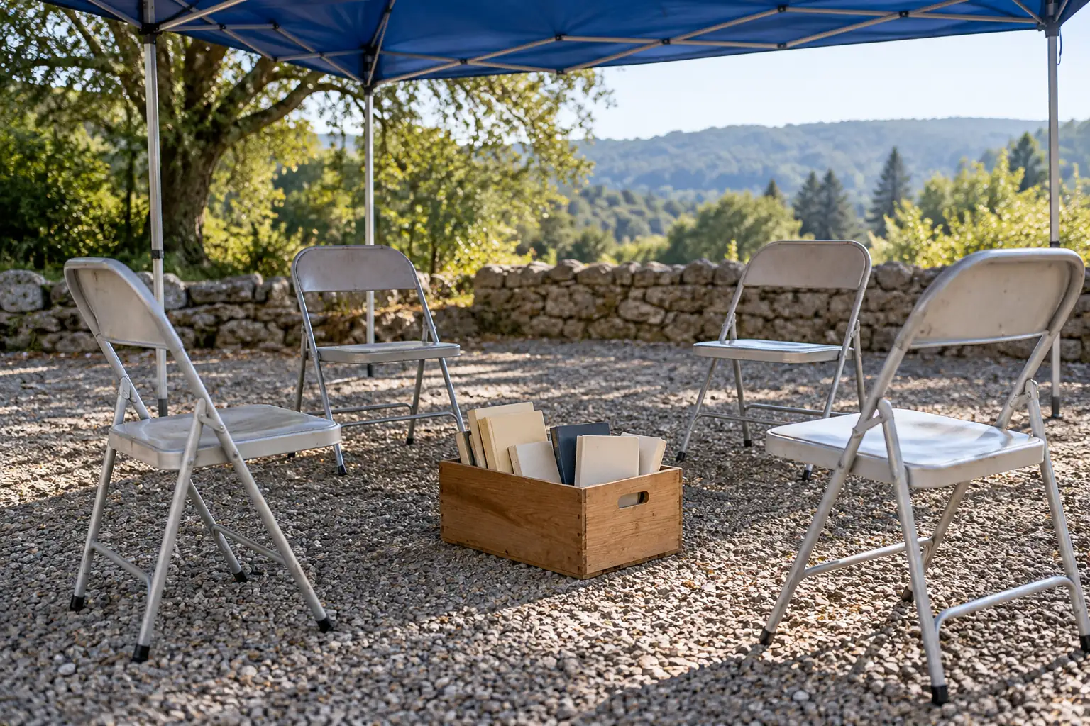 Illustration: Four aluminum folding chairs and an open crate of plain books sit under a blue canvas shelter on gravel, in a wide off-center view.
