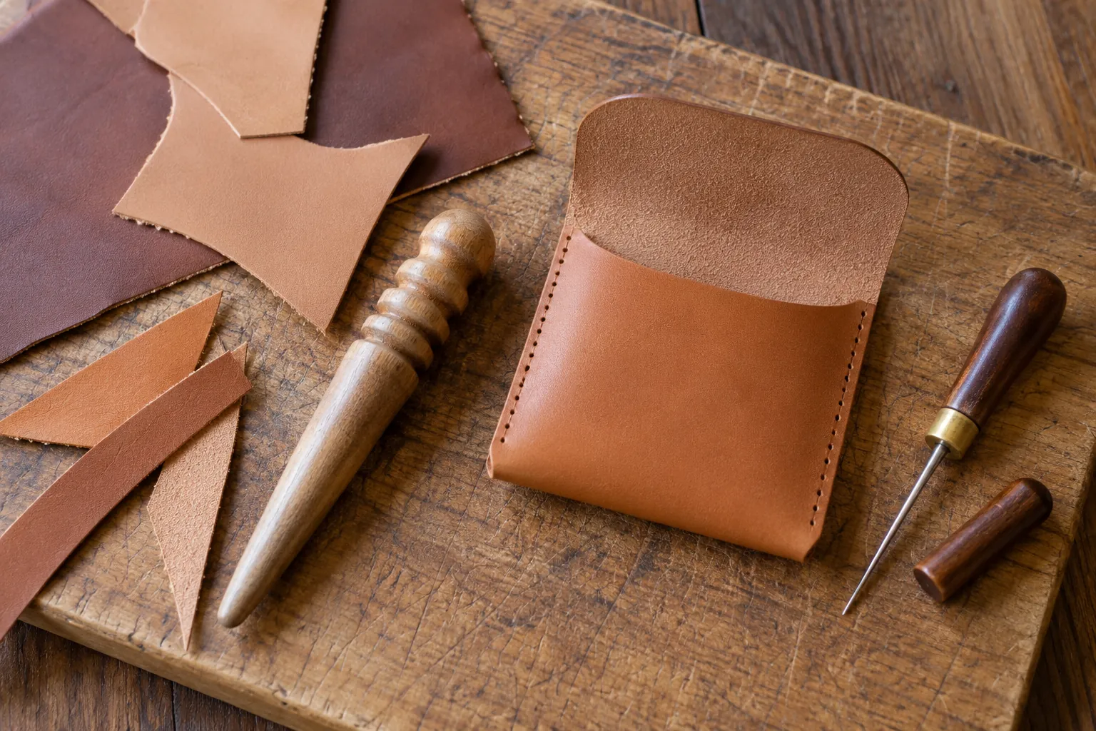 Illustration: Leather offcuts and simple hand tools beside an unfinished pouch.