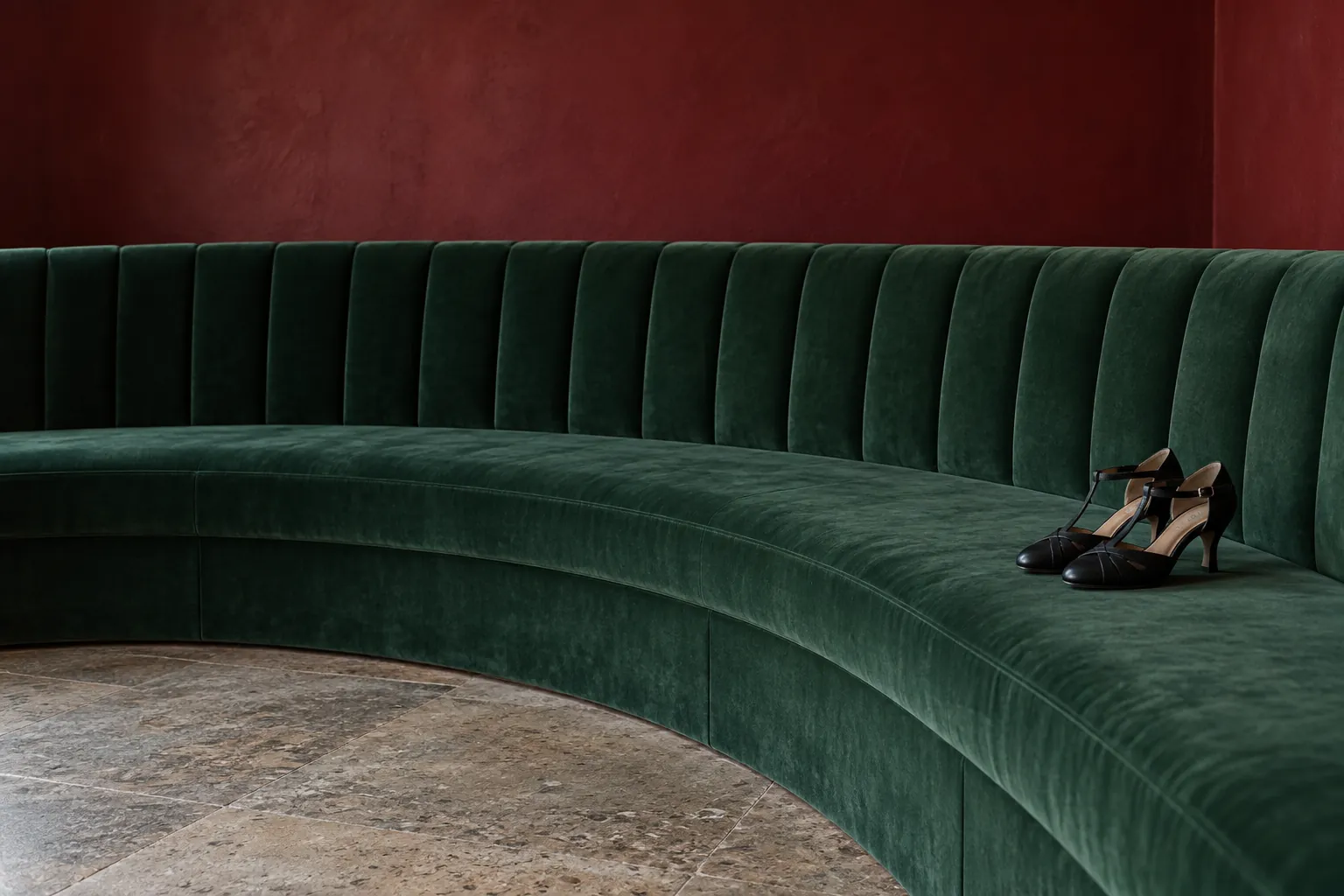 Black tango shoes on a curved green rehearsal bench.
