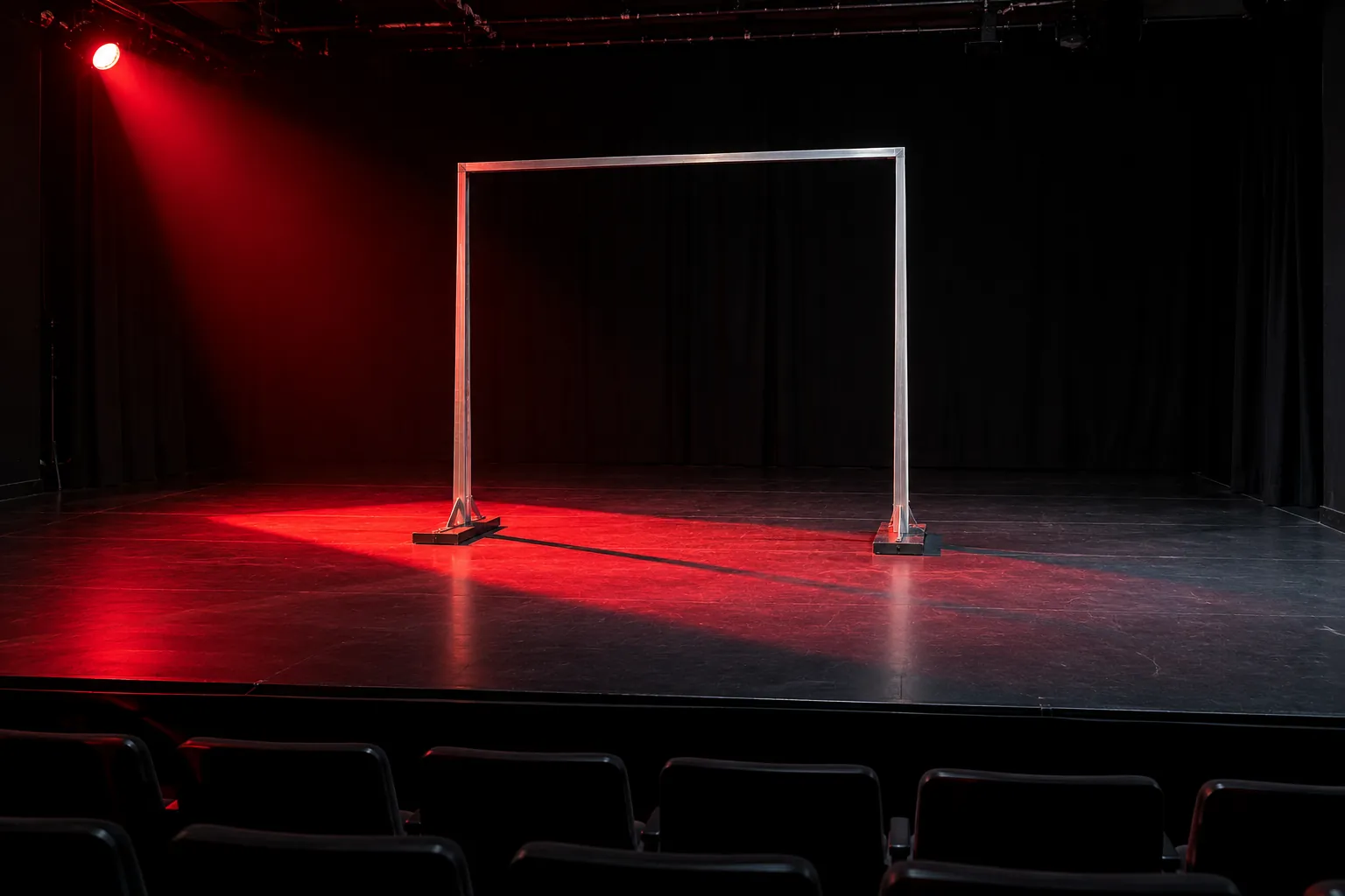 Illustration: An aluminum frame casting a long shadow on a black-box stage.