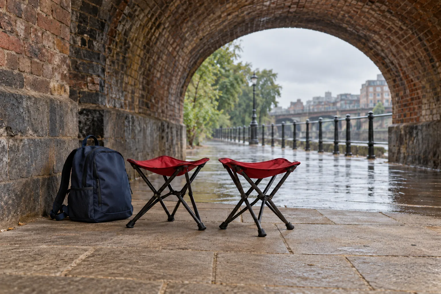 Illustration: Folding stools and a daypack sheltered beneath a brick viaduct.