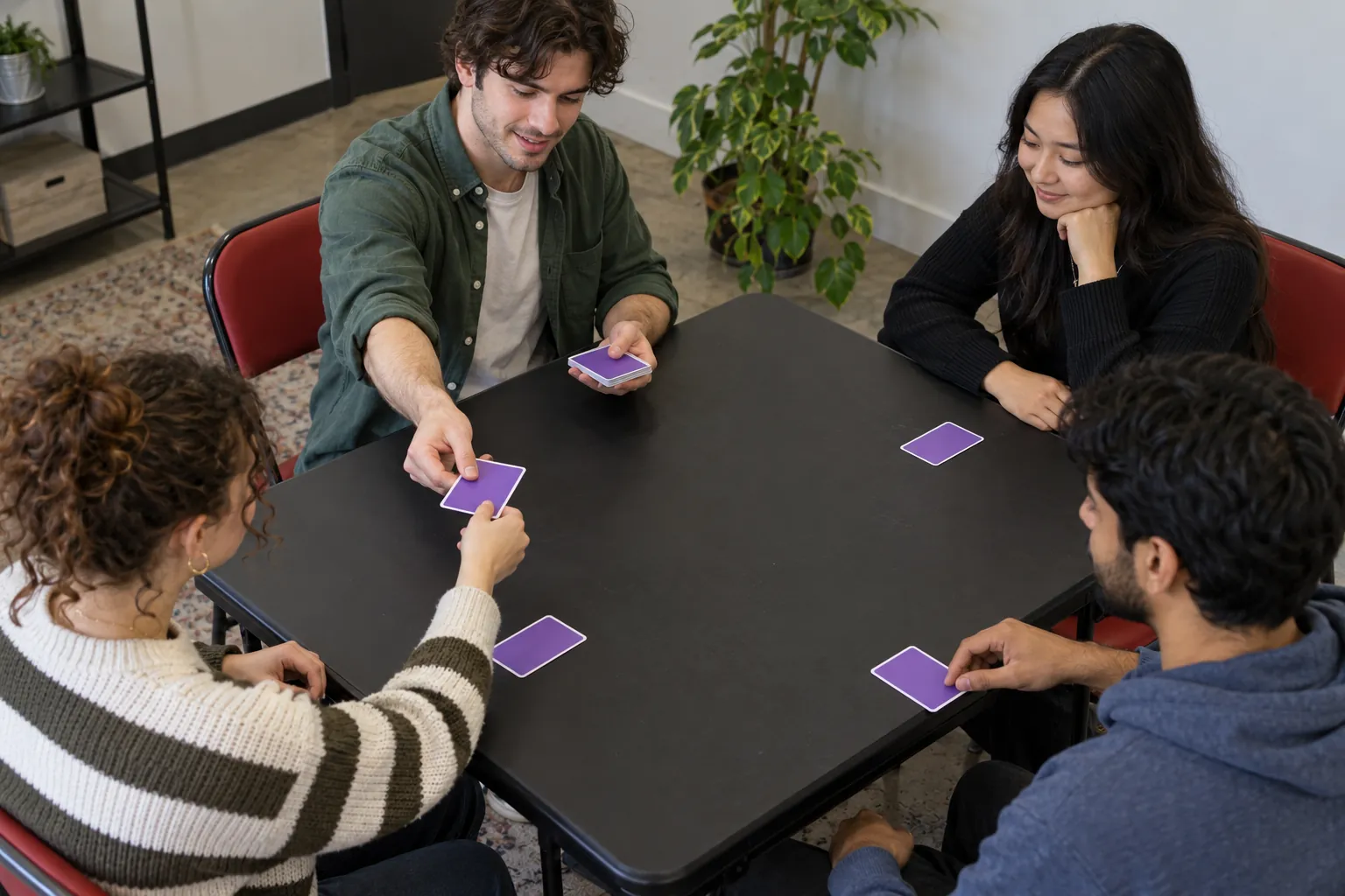Illustration: A player deals hidden-role cards to three other young adults.